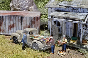 Miniature of farmer looking at workers carrying product goods to carÂ pick up in distribution warehouse factory.